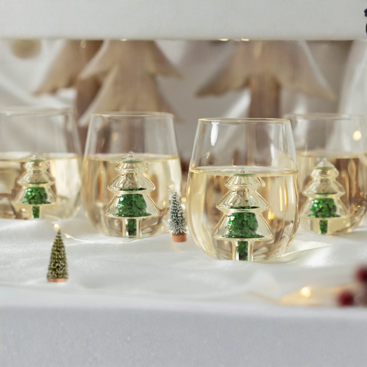 Wine glasses with Christmas tree decorations on a snowy surface