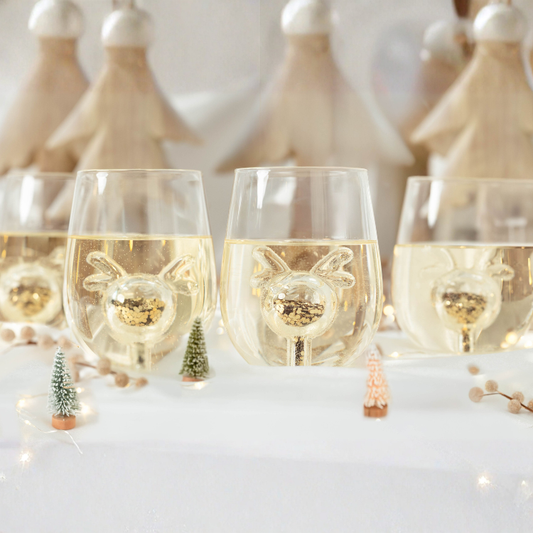Wine glasses with reindeer decorations on a festive table setting.