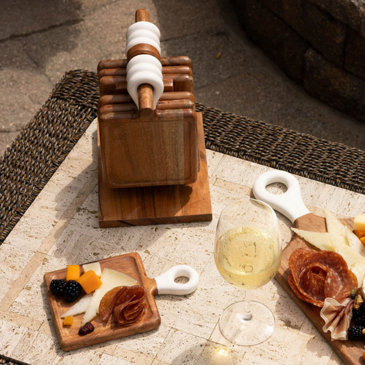 Wooden antipasto skewer set with a glass of white wine on a stone surface.