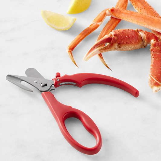 Red crab cracking tool with crab legs and lemon wedges on a white background