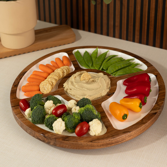 Wooden platter with various vegetables and hummus on a neutral background
