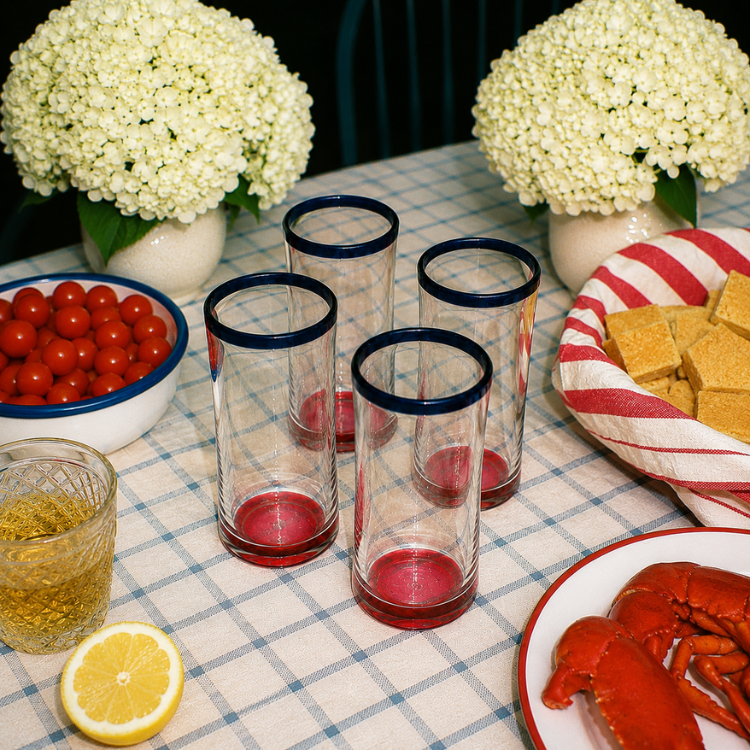 Table setting with empty glasses, lobsters, and flowers on a checkered tablecloth.