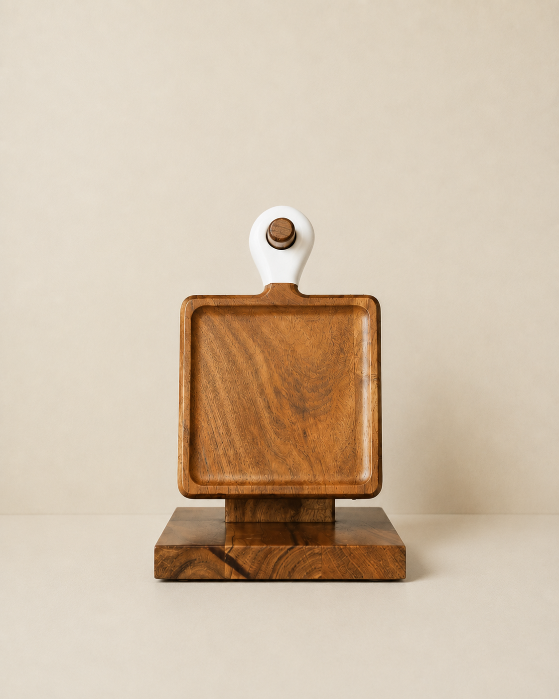 A square wooden serving board with a white loop handle and a matching wooden base, photographed against a plain beige background.