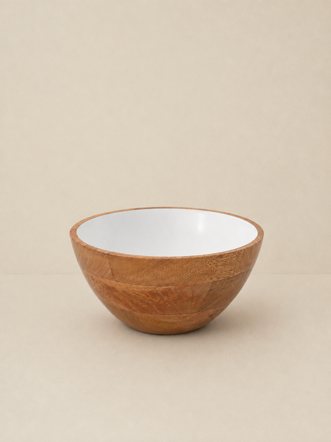 A small wooden bowl with a smooth white interior, photographed against a plain beige background.