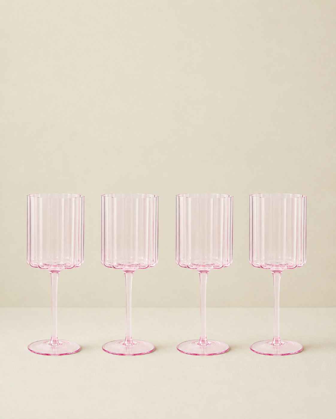 Set of 4 pink scalloped glasses on a cream background
