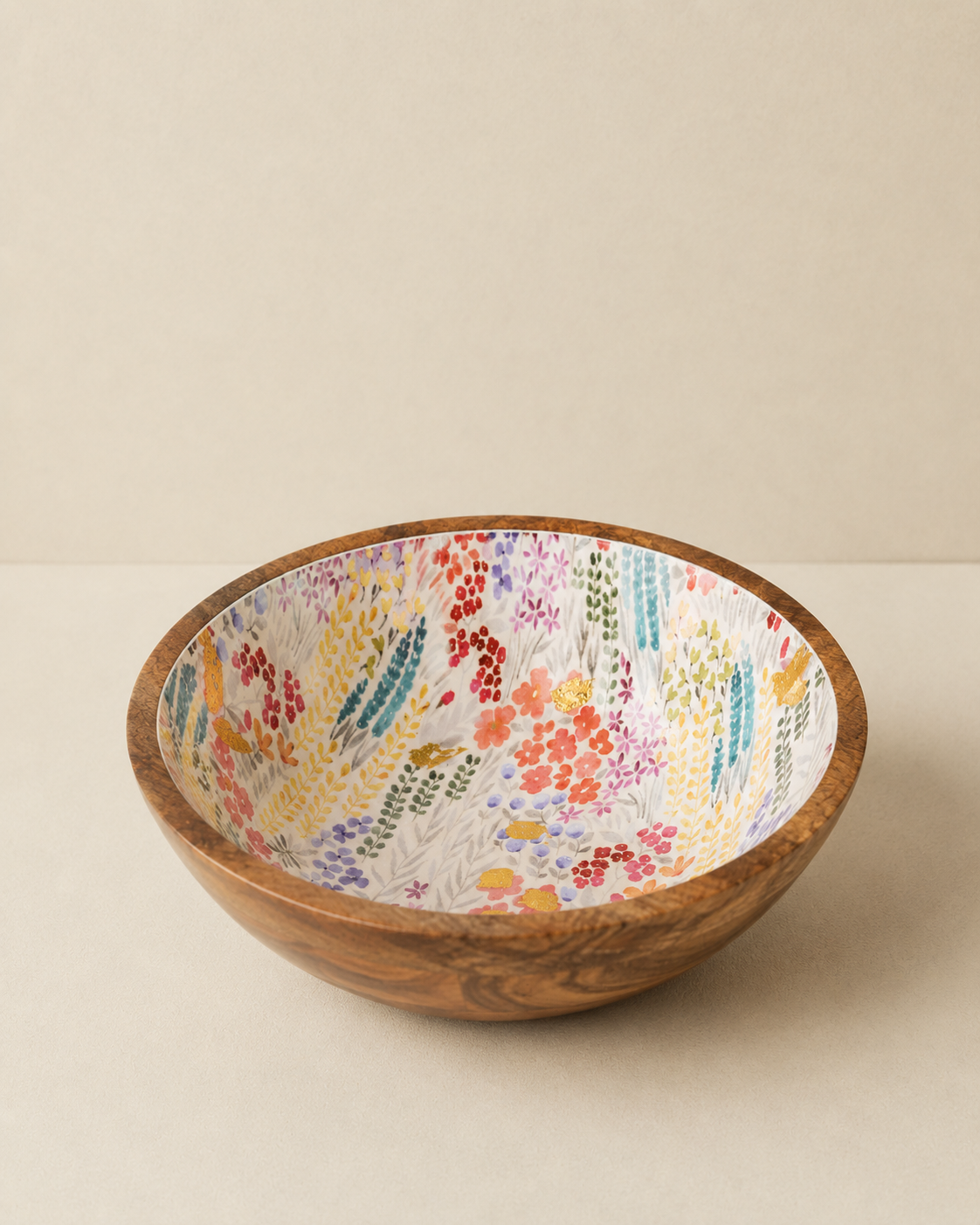 A round wooden bowl with a colorful hand-painted floral pattern on the inside, set against a neutral beige background.