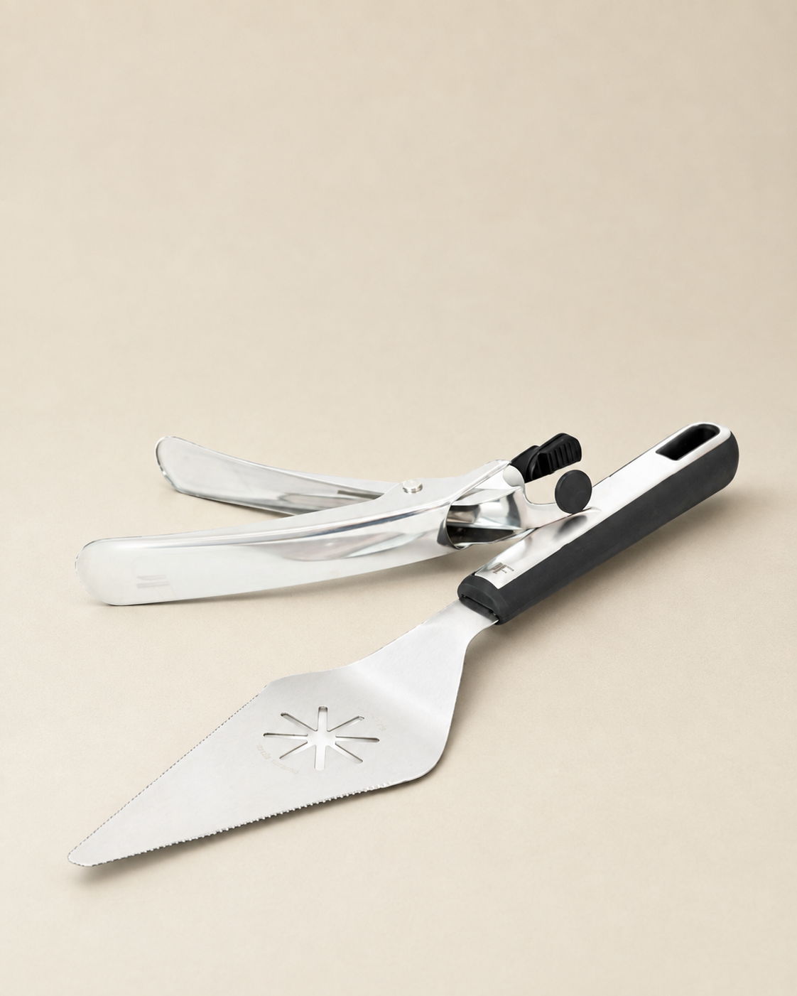 A stainless steel cake server and spatula set with a black handle, displayed on a solid beige background.