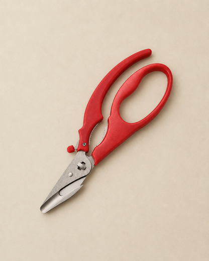 Red-handled pruning shears with silver metal blades, photographed diagonally on a solid beige background.
